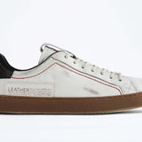 Side profile of low top white sneaker with black accent. Distressed white leather upper with red stitching and dark rubber sole.