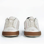 Front view of low top white sneaker with black accent. Distressed white leather upper with red stitching and dark rubber sole.