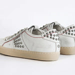Back view of low top white studded sneaker. Aged white leather upper with silver studs and natural rubber sole.