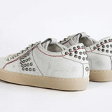 Back view of low top white studded sneaker. Aged white leather upper with silver studs and natural rubber sole.