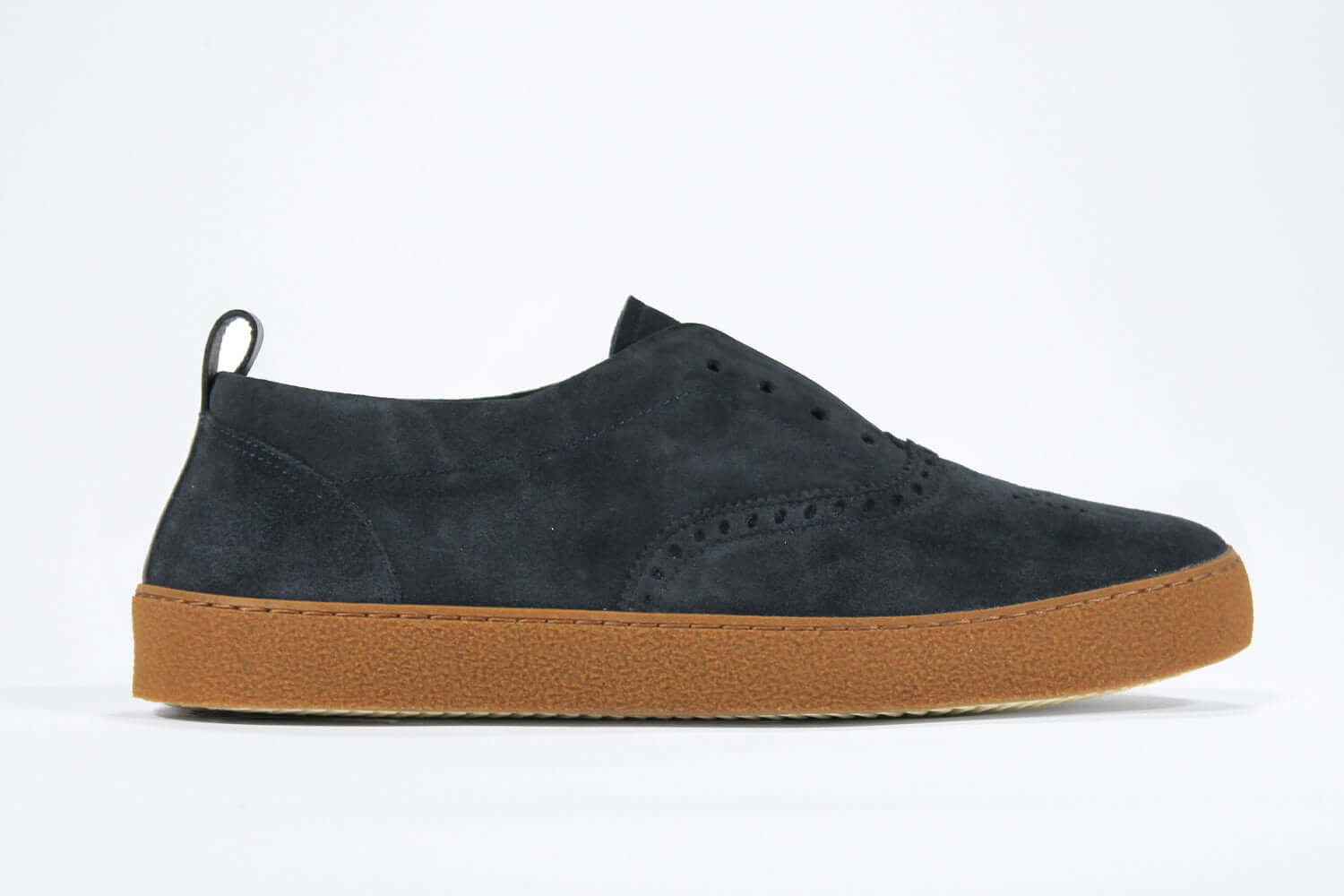 Side view of loafer style sneaker. Navy suede upper with perforated crown logo, elasticated tongue and a honey coloured recycled rubber sole.