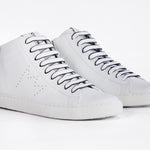 Three quarter front view of mid top white sneaker with full leather upper with perforated crown logo and white sole.